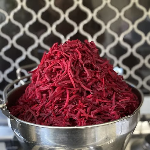 A bowl full of grated red beetroot in front of a wire mesh