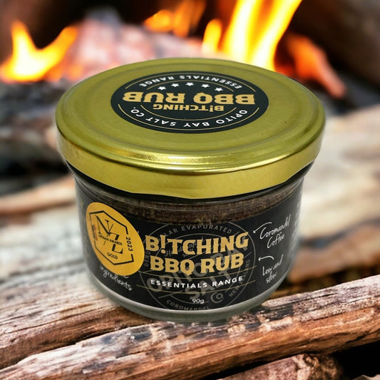 Jar of BBQ rub with a gold lid on wooden logs with flames in the background